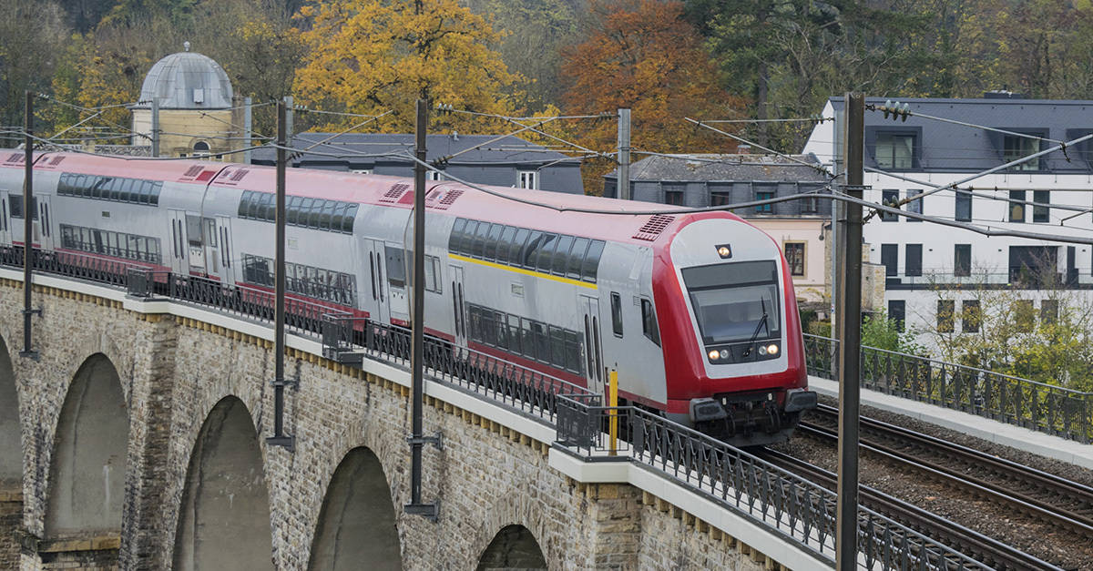 Detail of electrical railroad in Luxembourg city with train, rails, contact lines and viaduct structures in dark autumn day illustrating urban transport concept, Luxembourg.